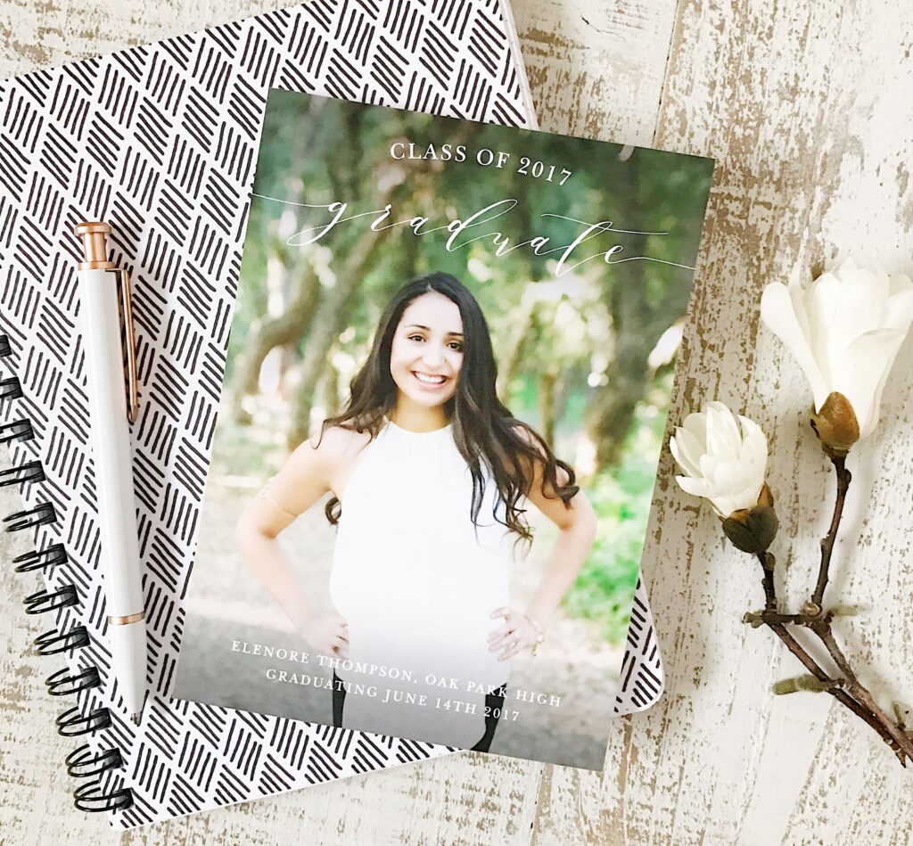 "Class of 2017 Graduate" announcement card with photo, resting on a notebook.