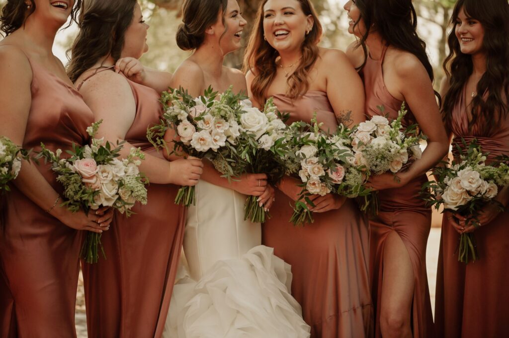 Bride Laughing with Bridesmaids Holding Wedding Bouquets