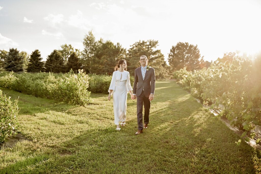 Bride and Groom Walking Through Vineyard After Wedding Ceremony