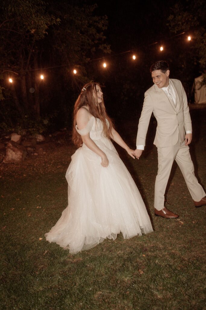 Bride and groom holding hands, laughing.