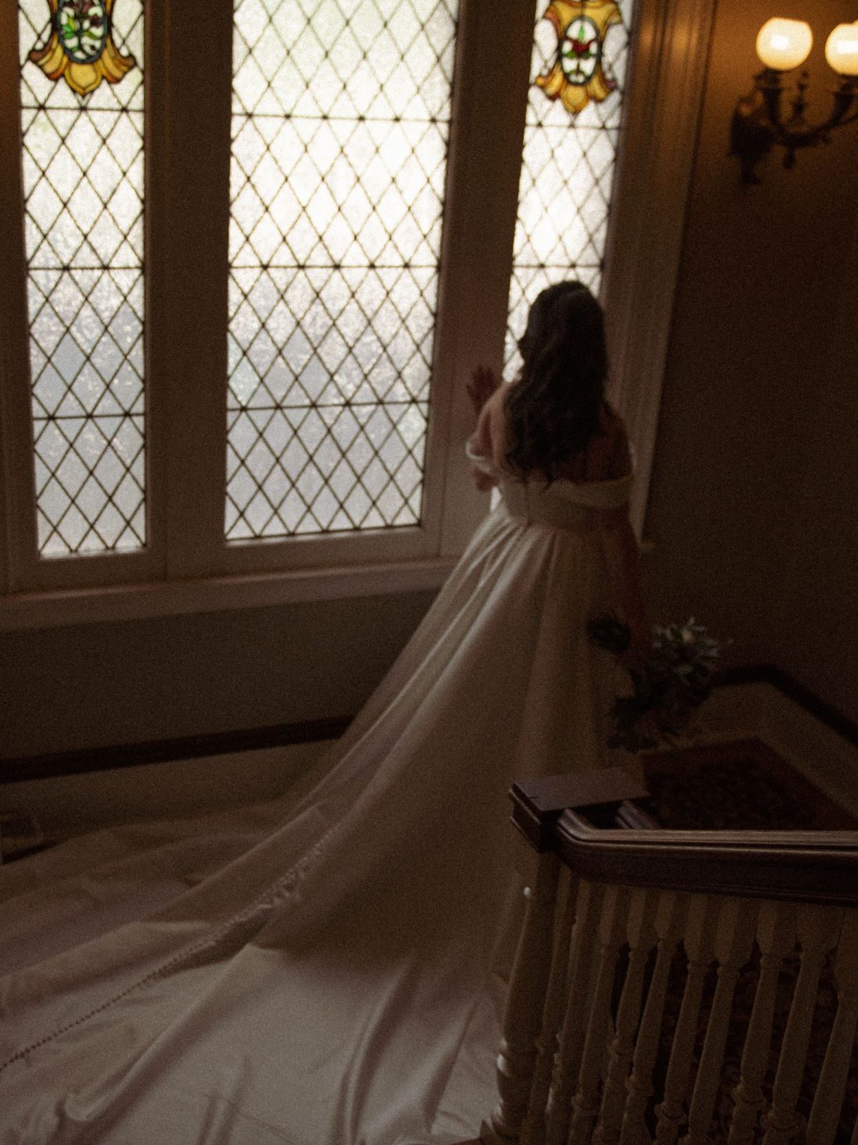 Bride standing at a stained-glass window.