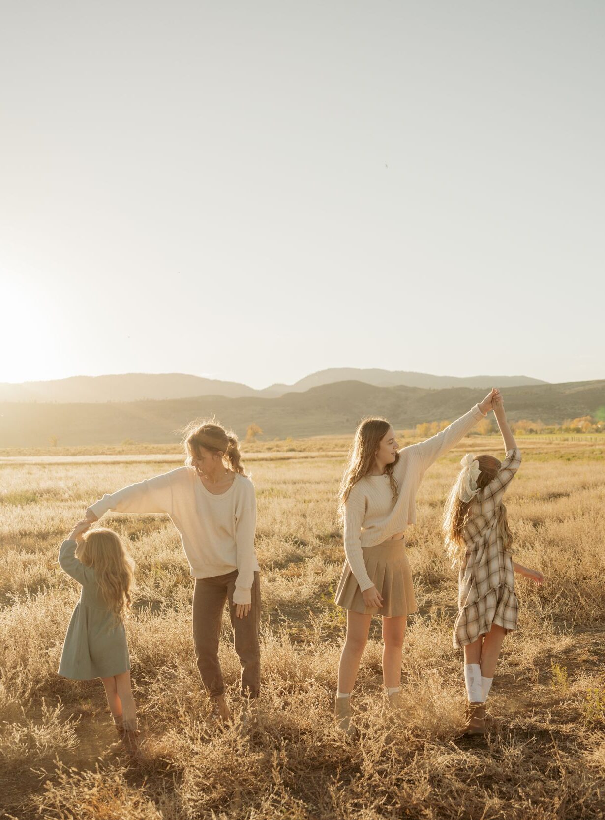 Children twirling in a golden field at sunset.
