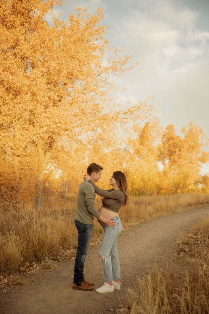 Couple embracing during an outdoor fall maternity photoshoot