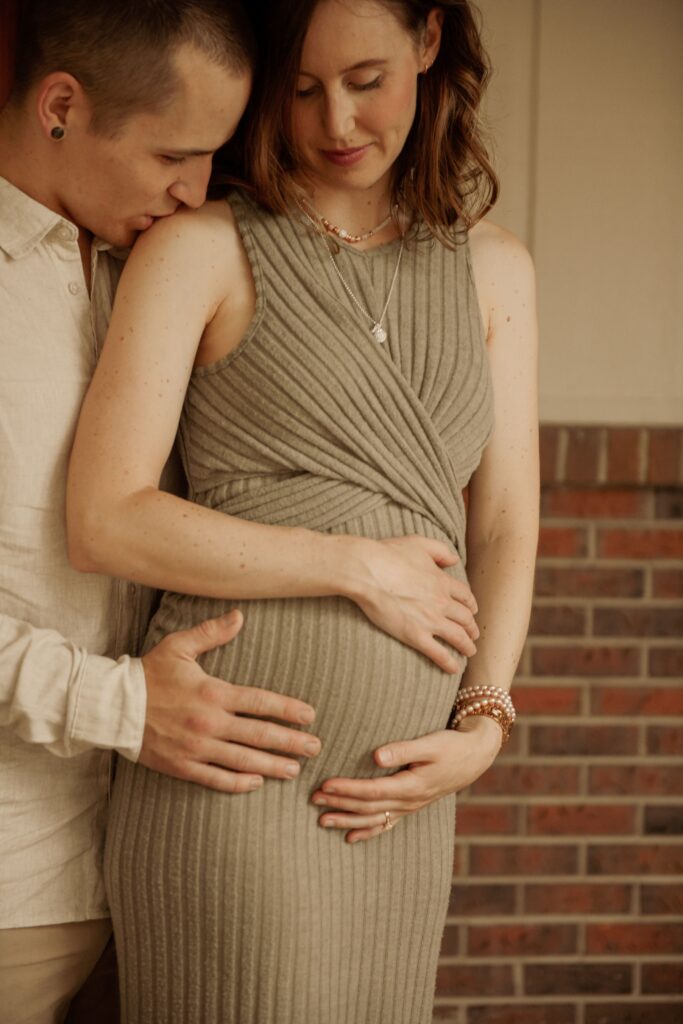 Couple embracing, hands on her baby bump.
