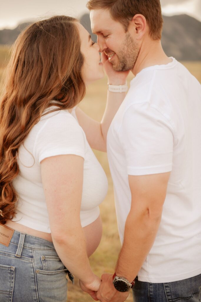 Couple sharing a kiss in a field.