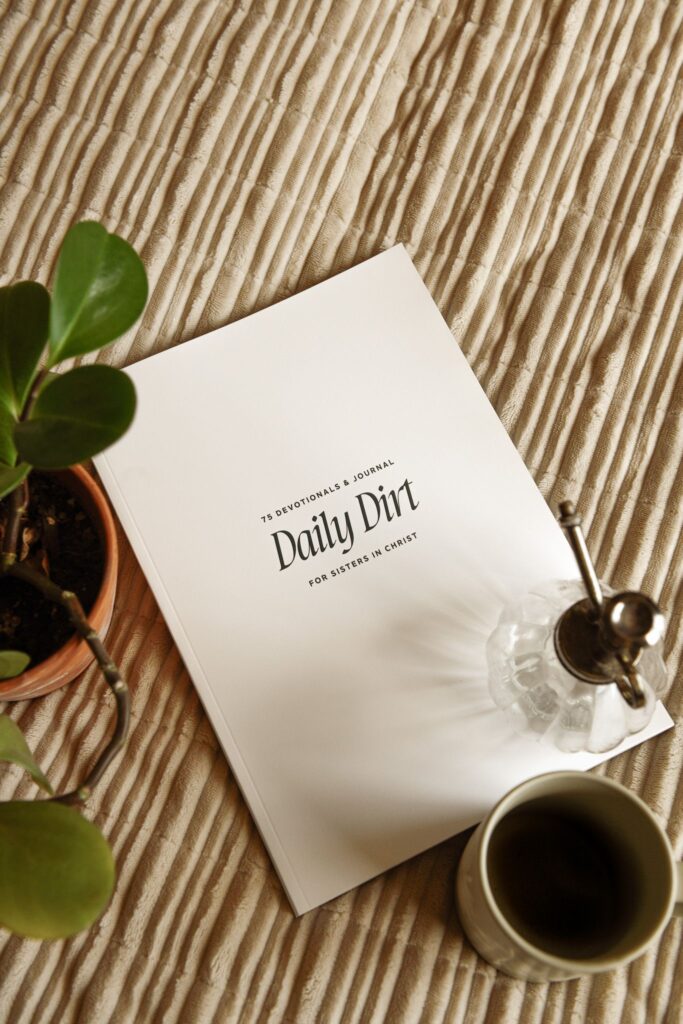 Daily Dirt devotional journal with coffee and plant on a textured blanket