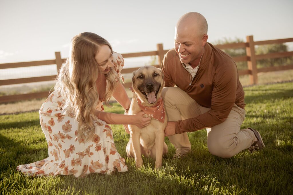 Couple smiling with their dog during an outdoor engagement session.