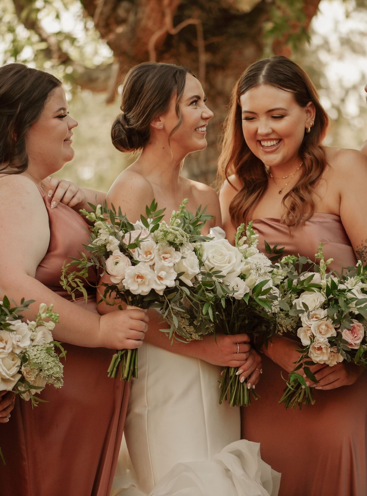 Bride laughing with bridesmaids during wedding portraits.