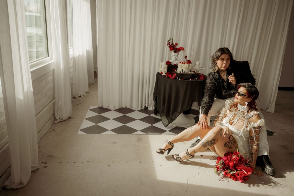 Couple posing with bold modern wedding styling in a sunlit studio.