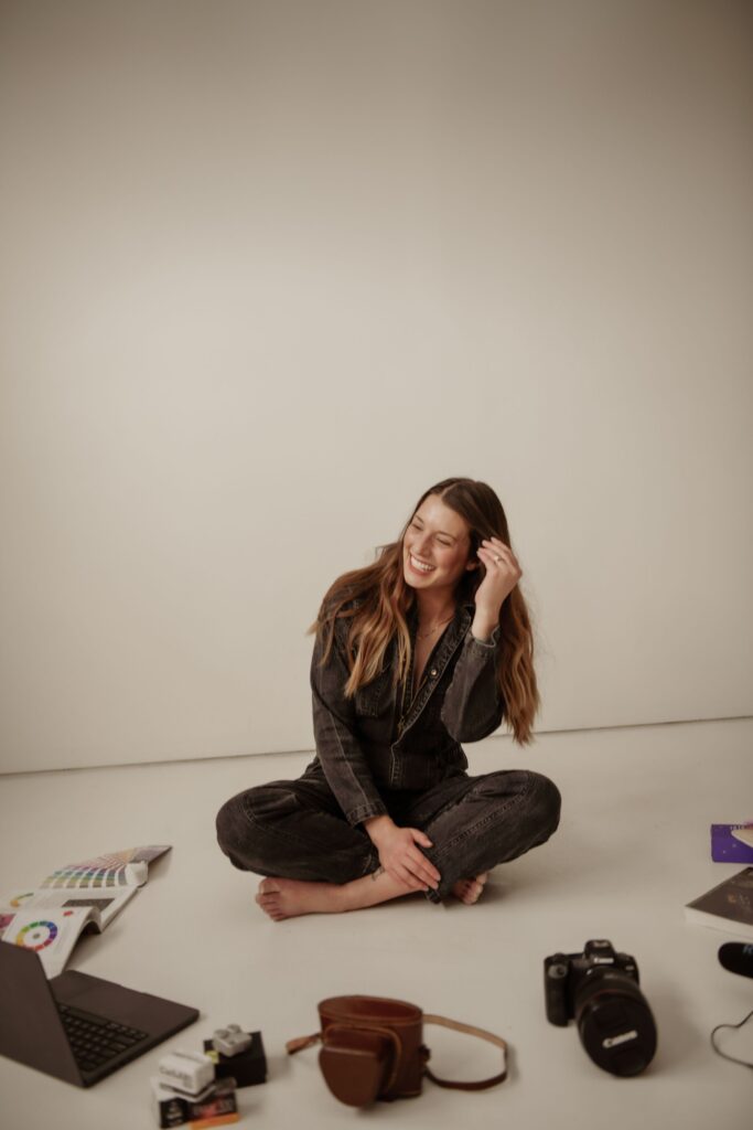 Photographer sitting in a studio surrounded by camera gear and editing tools.