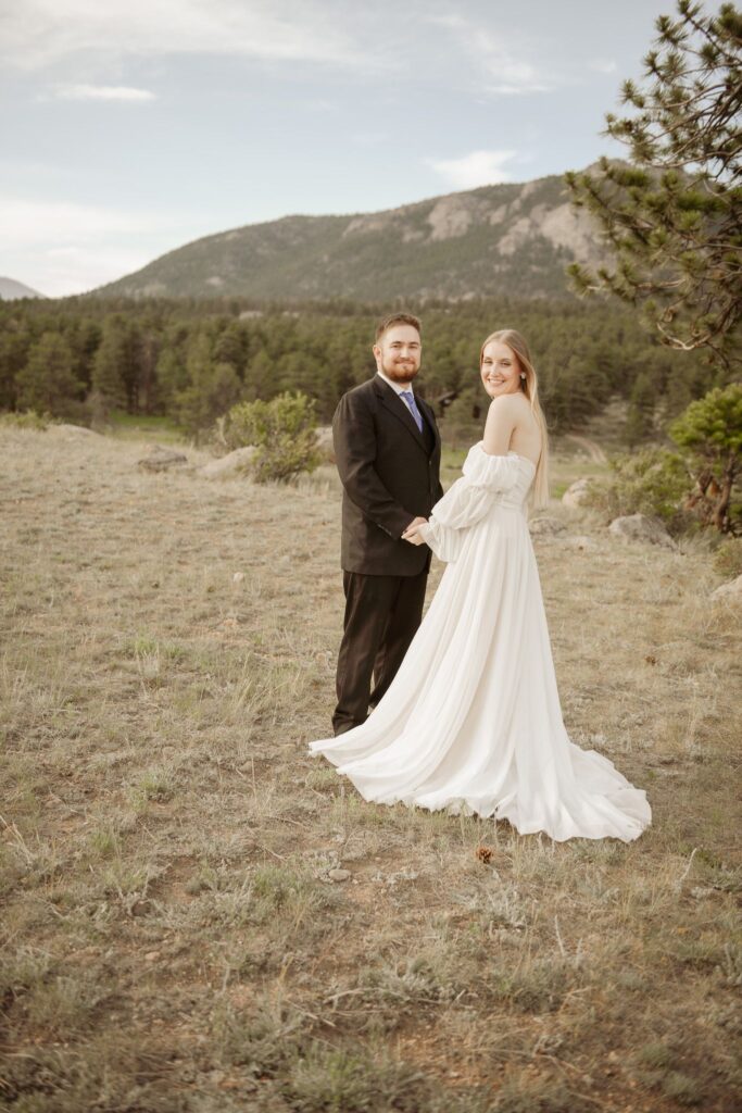 Bride and groom holding hands with mountains in the background.