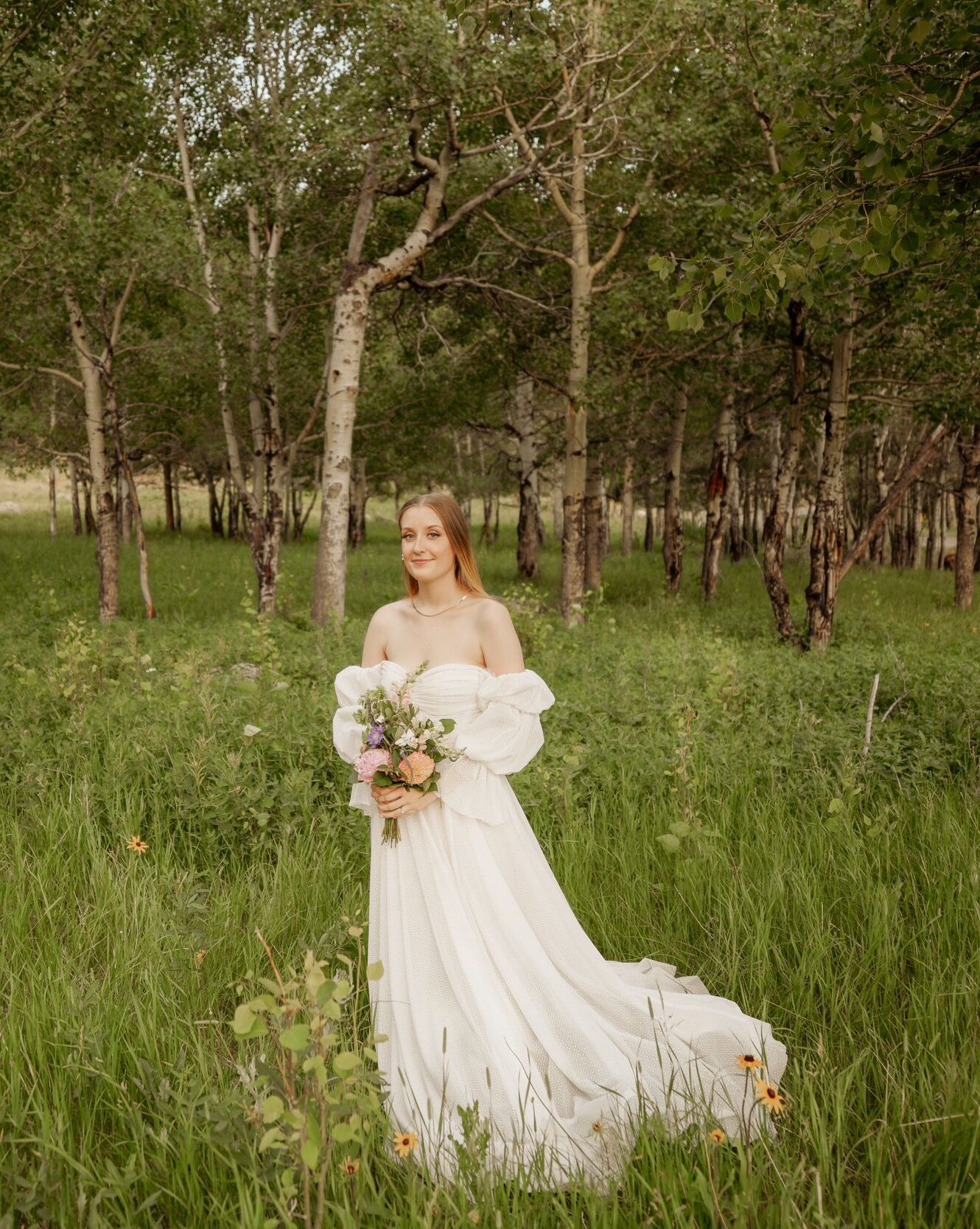 Bride holding a bouquet in a white wedding dress surrounded by a peaceful forest.
