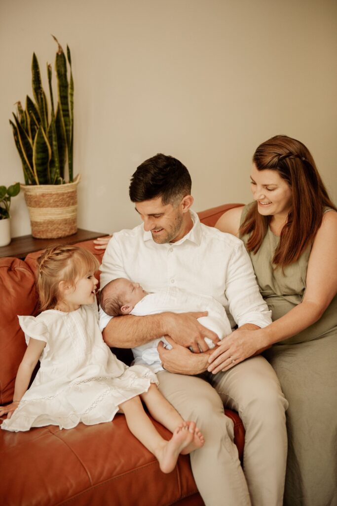 Family gathered together with their newborn baby on a couch.