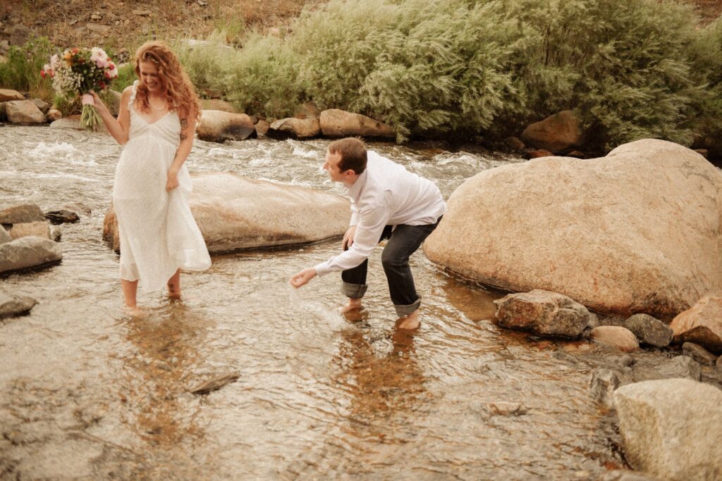Couple playing together in a shallow river during an engagement session.