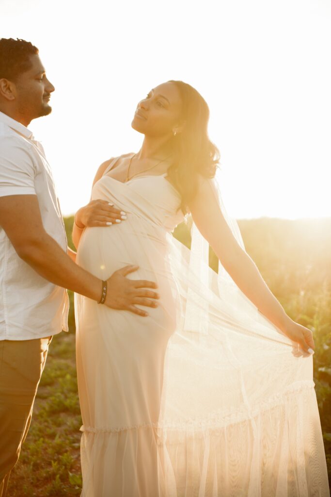 Pregnant couple embracing during a golden hour maternity photoshoot outdoors.
