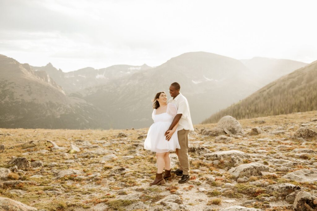 Couple embracing on a rocky mountaintop at sunset.