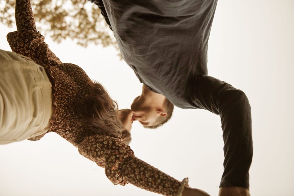Upside-down close-up of a couple kissing outdoors.
