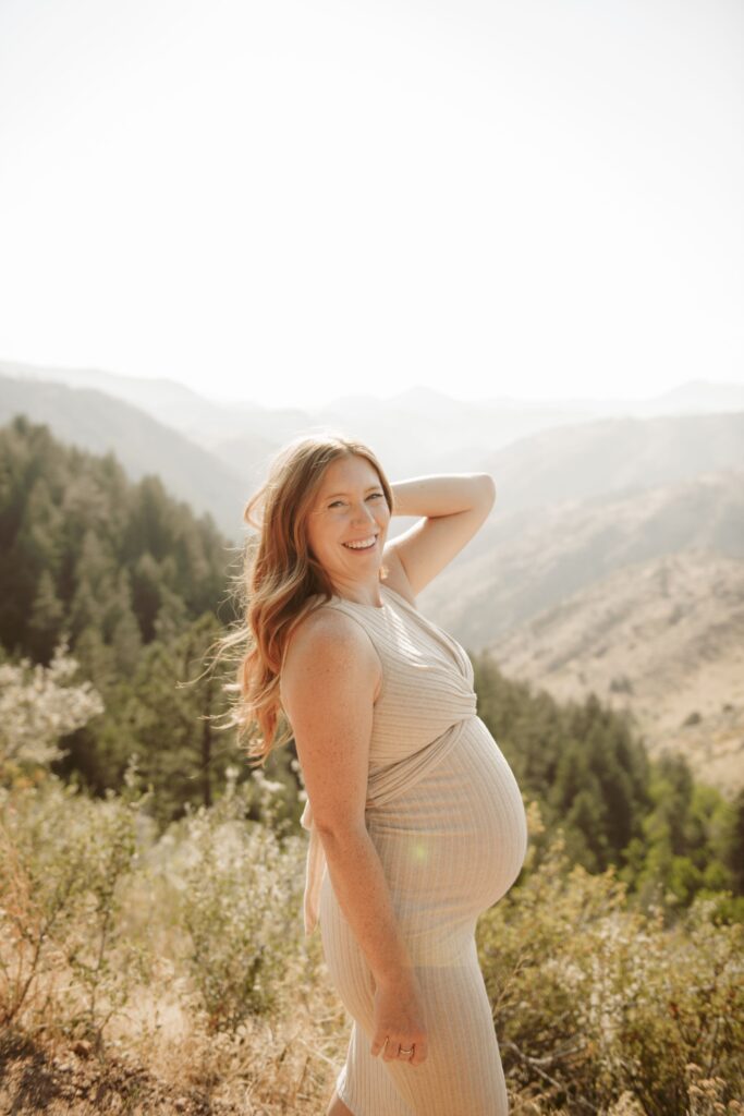 Pregnant woman smiling in front of mountains.