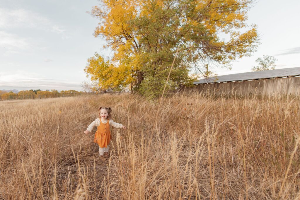 Toddler running through a fall field.