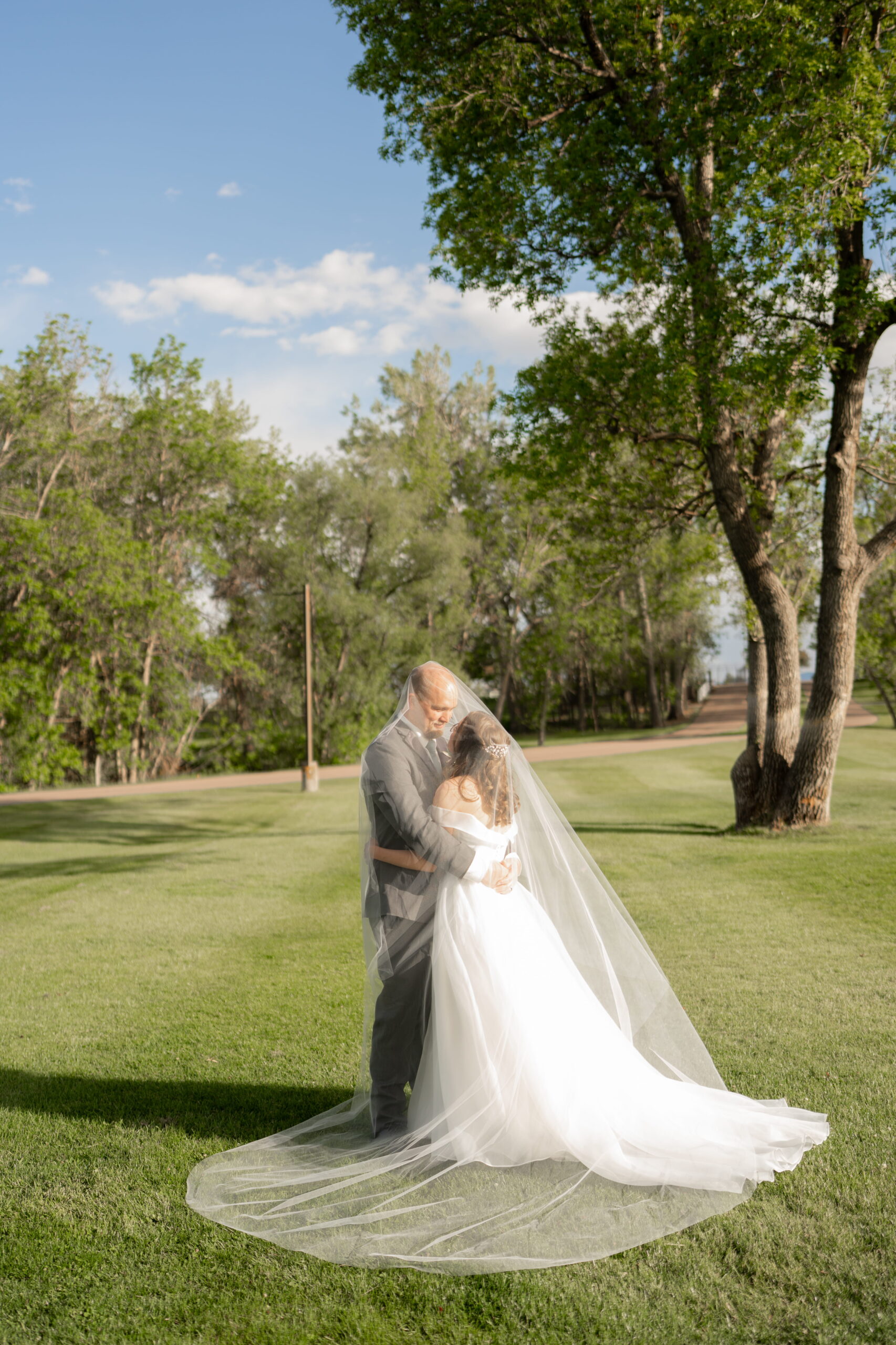 Bride and groom embracing beneath the veil at sunset