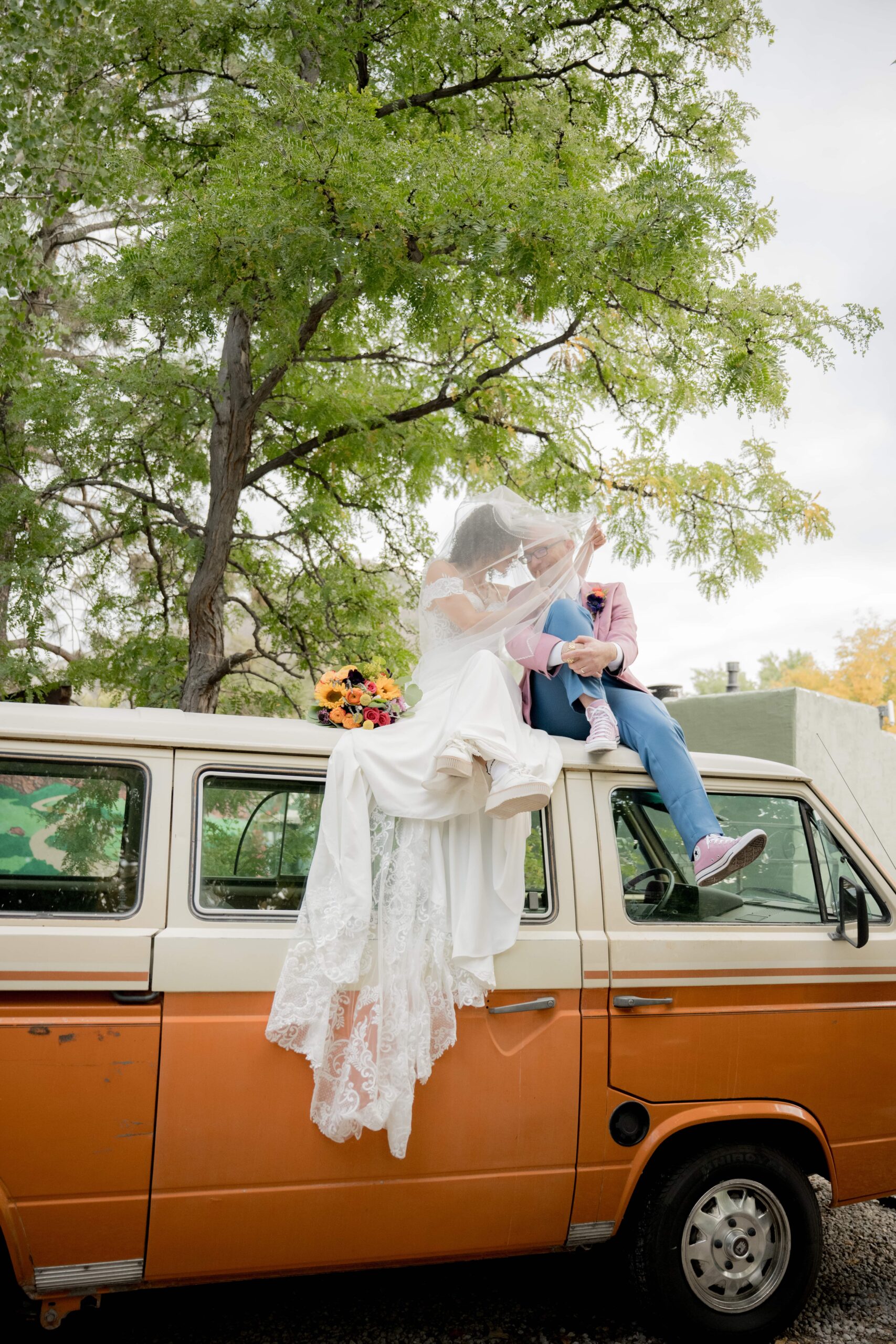 Bride and groom sitting on a car